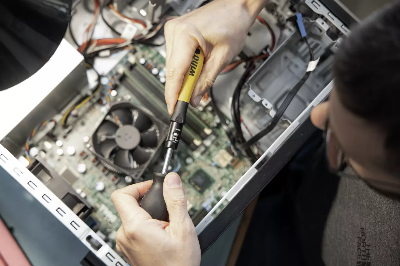 Personne utilisant un tournevis dynamométrique dans un boîtier d'ordinateur