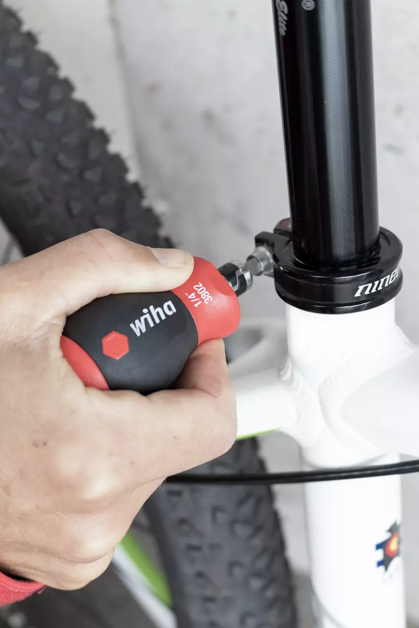 Person using a stubby screwdriver on a bicycle seat post clamp.