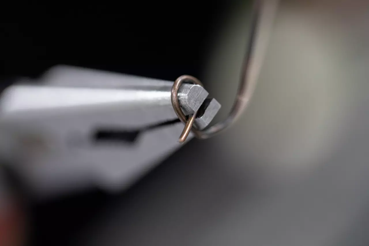 Close-up van een tang die een gebogen metalen draadlus vasthoudt