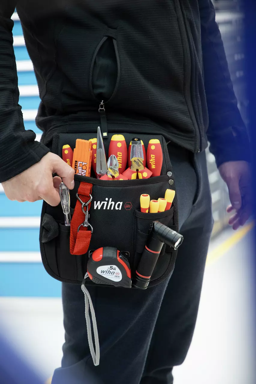 Electrician's tool pouch with various tools, including screwdrivers, pliers, and a tape measure.
