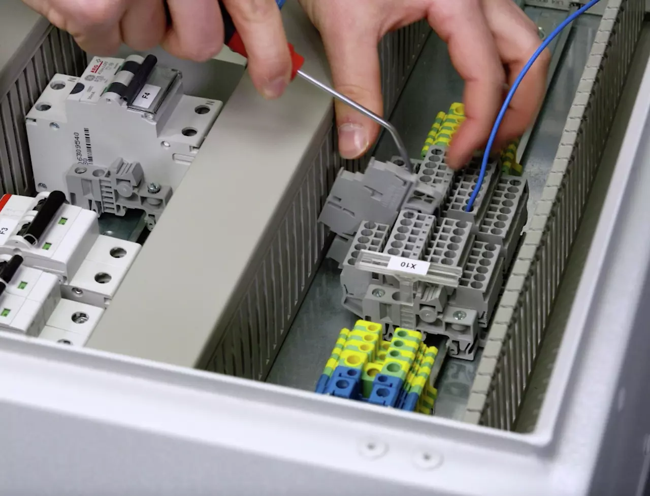 A person using a screwdriver in an electrical terminal block.