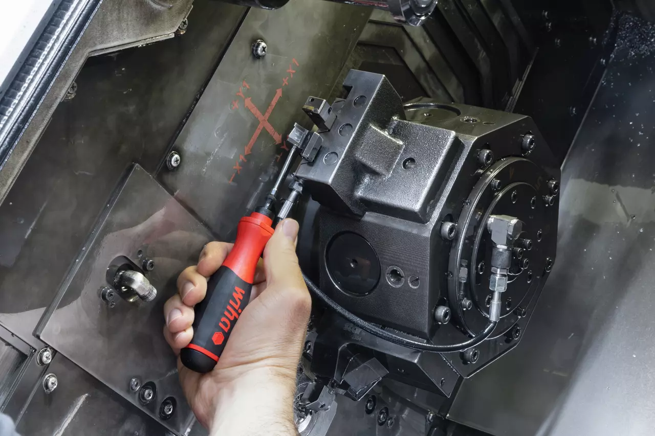 Person using a torque screwdriver on a CNC machine component.