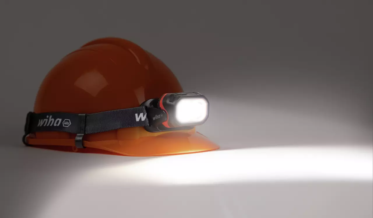 Orange hard hat with an attached headlamp emitting bright light.