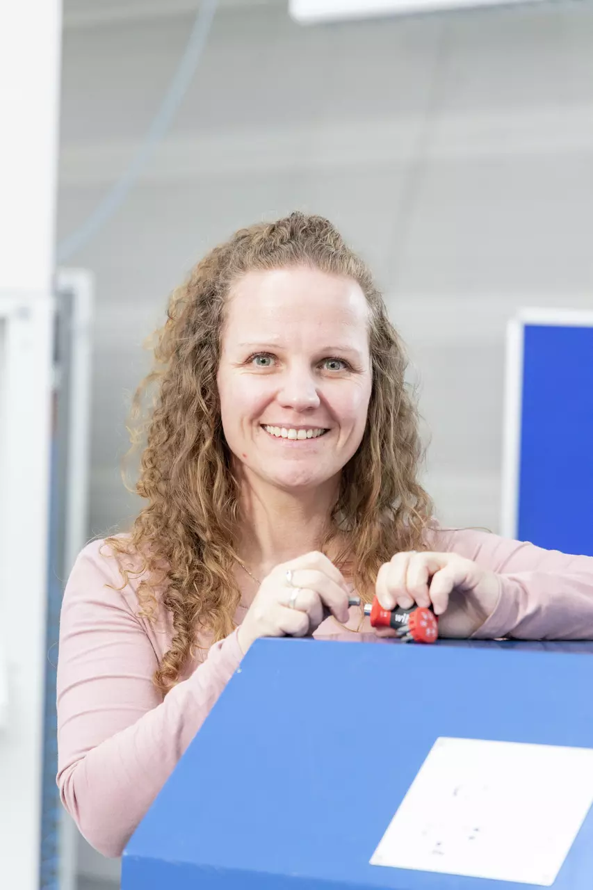 A person working with a screwdriver on a blue machine.
