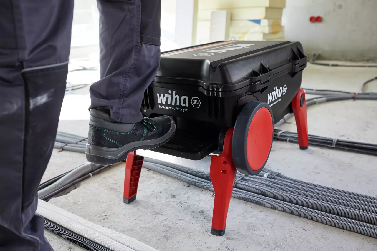 Person stepping onto black toolbox with red legs