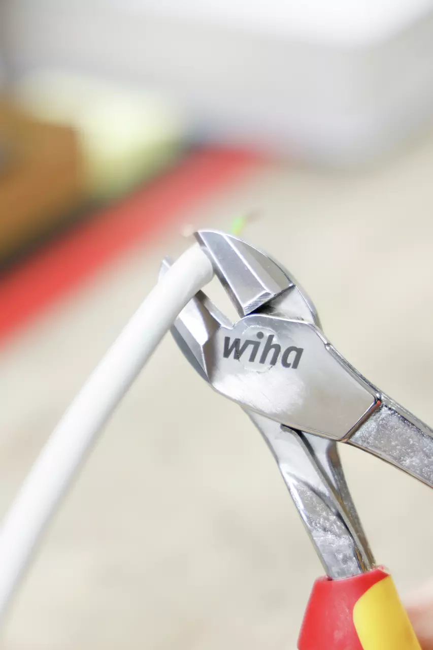 Close-up of a side cutter cutting a white cable