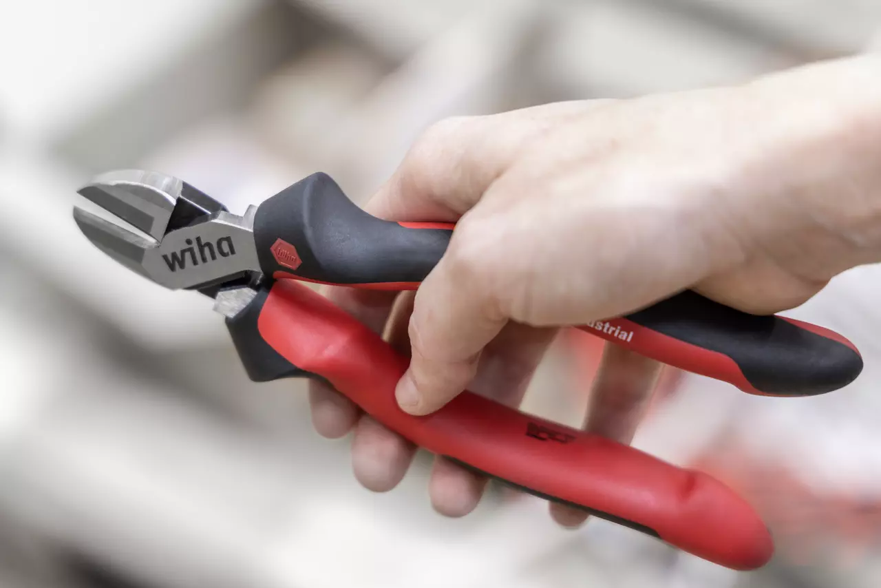 Hand holding red and black wire cutters with a metal blade