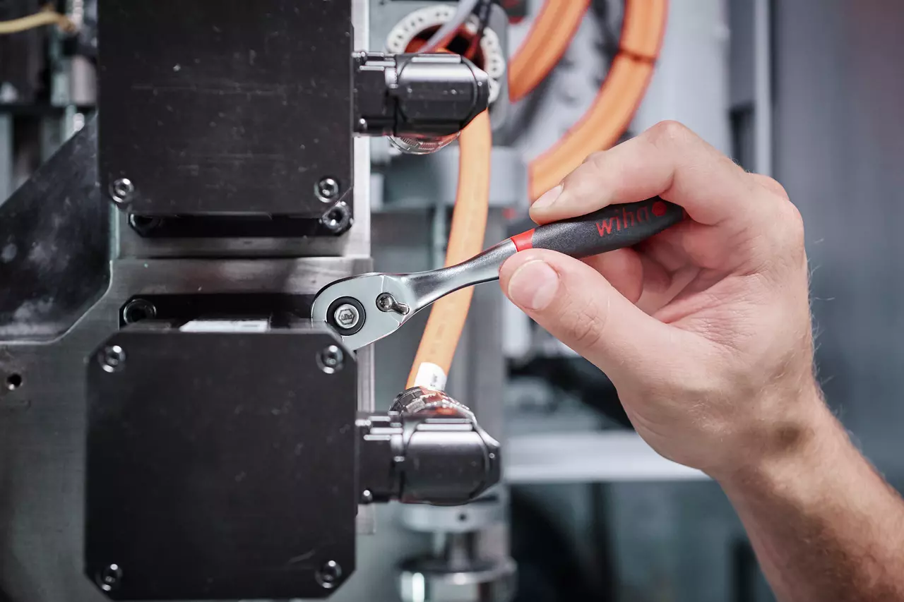 A hand using a ratchet wrench on machinery