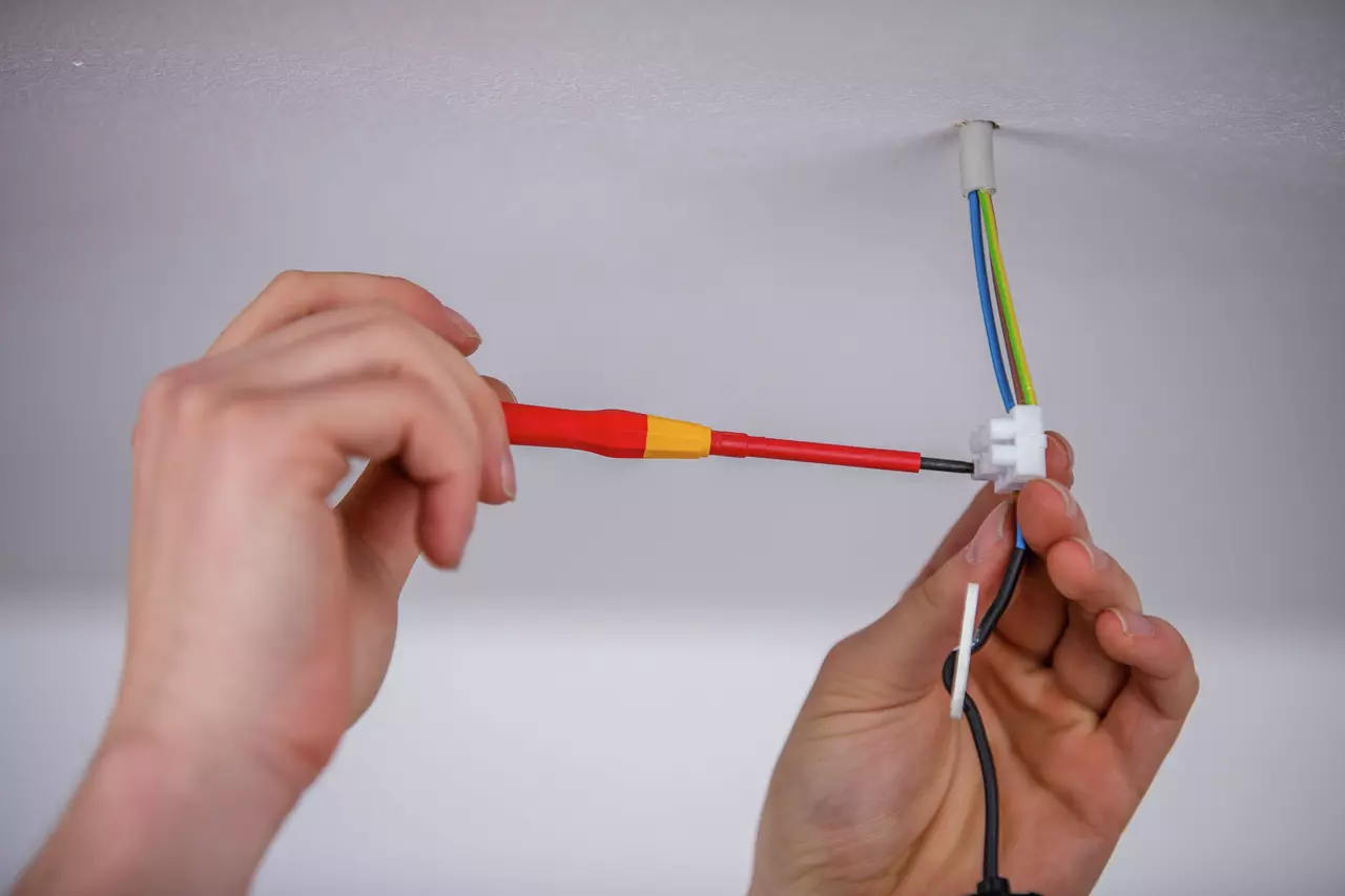 Person using a precision screwdriver to connect electrical wires