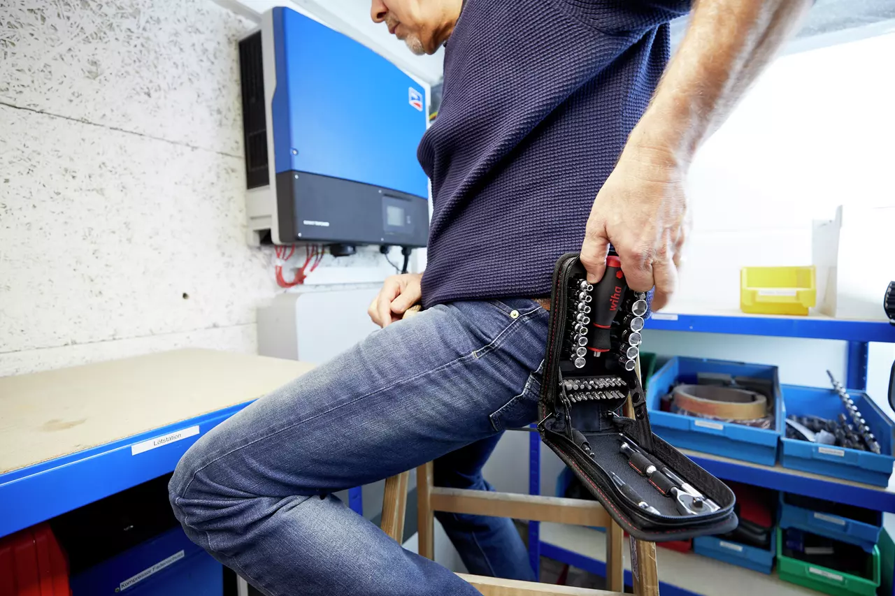 A person holding a socket set in a case in a workshop.