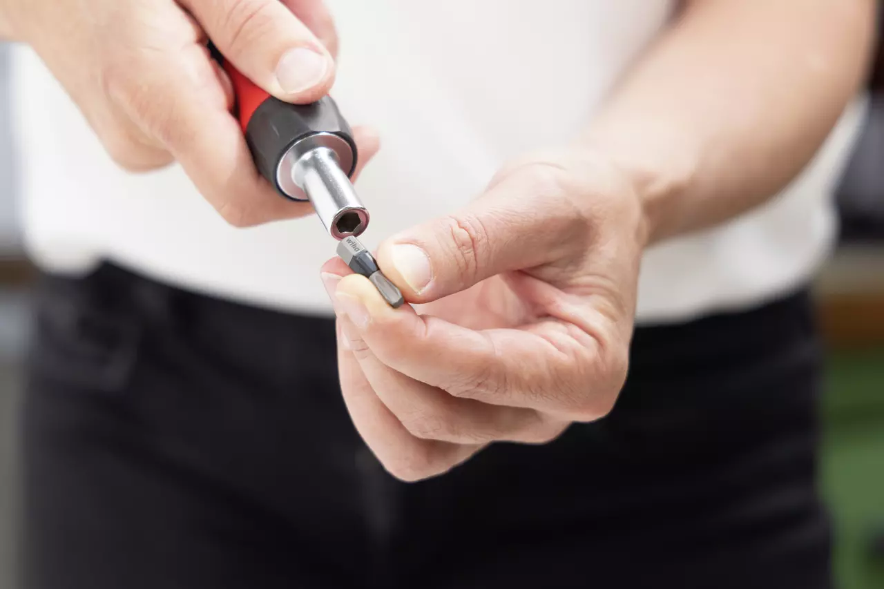 Person inserting a screwdriver bit into a magnetic bit holder.