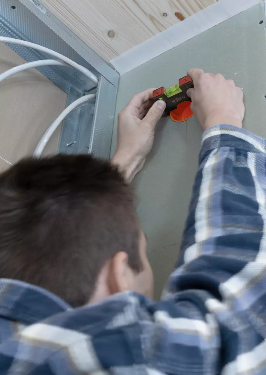 Person using a small spirit level on a wall near ceiling