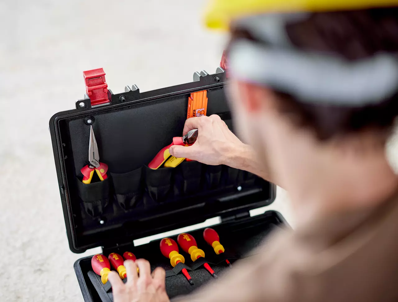 Person accessing tool set with red and yellow handles in a black case