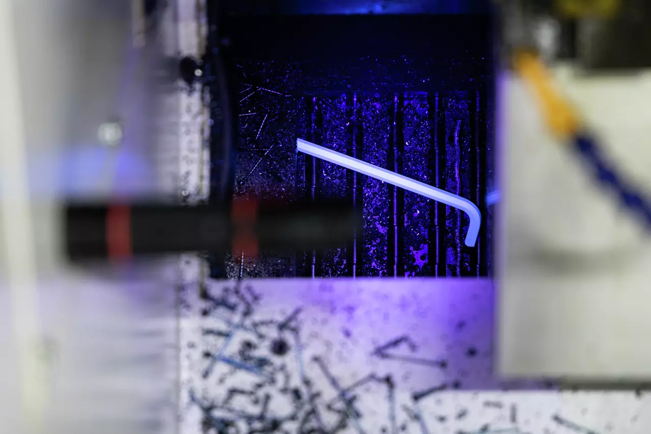 A glowing L-shaped tool on a dark surface with scattered metal shavings.