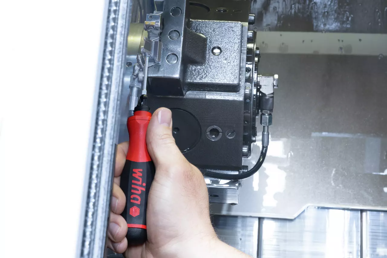 Hand using electric screwdriver on CNC machine part