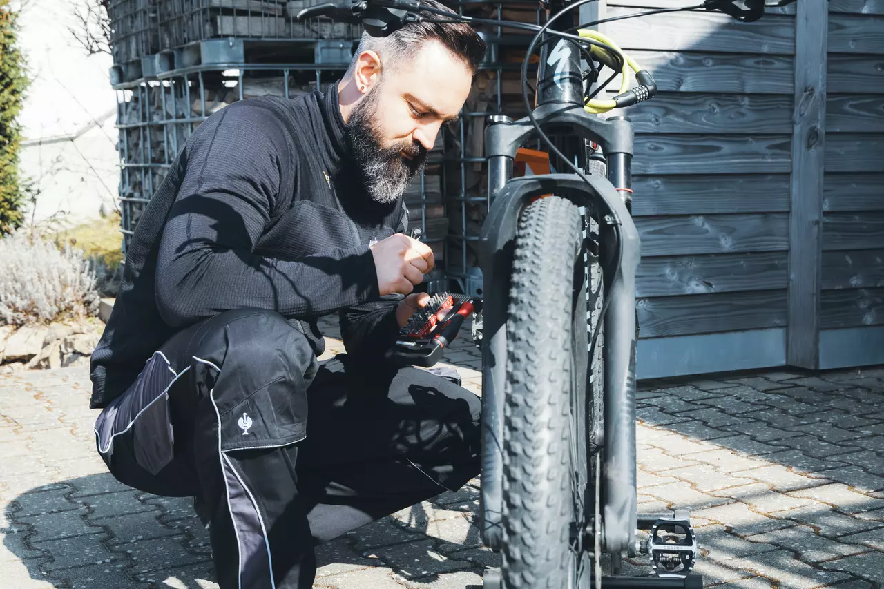 A person is working on a bicycle using a tool kit outdoors.