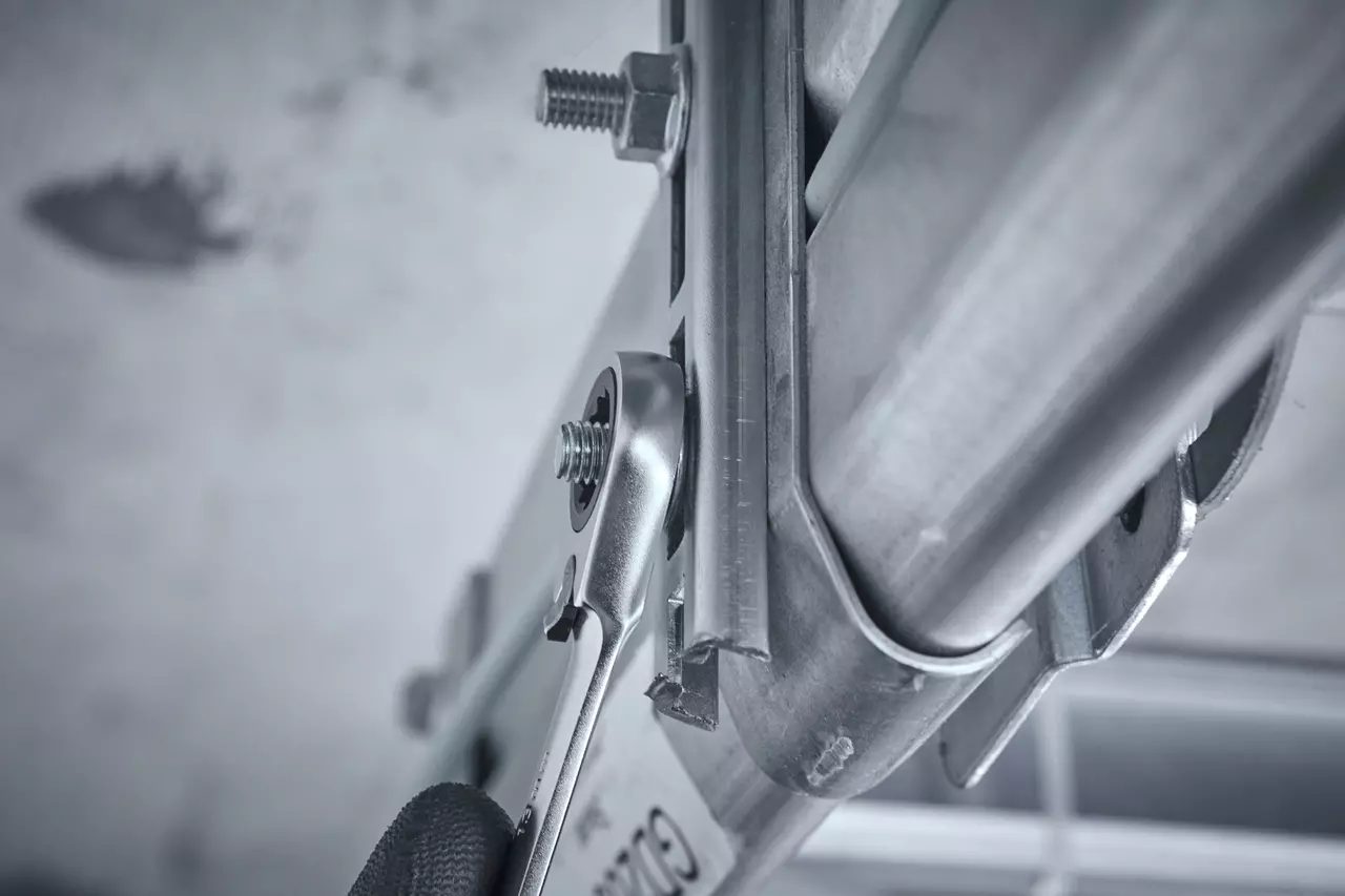 A reversible ratchet wrench is used to tighten a bolt on a metal structure.