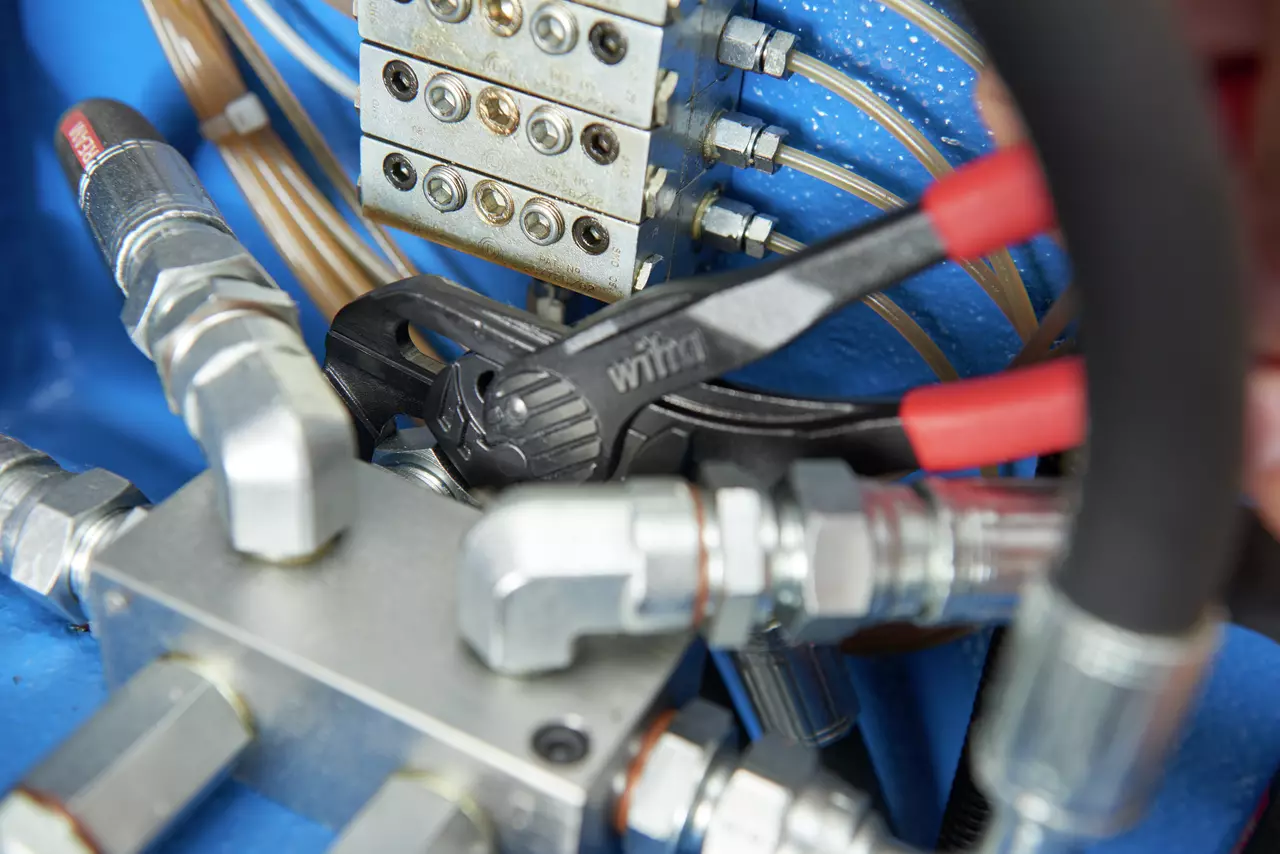 Nastavitelné kleště uchopující kovovou armaturu mezi hydraulickými spoji.