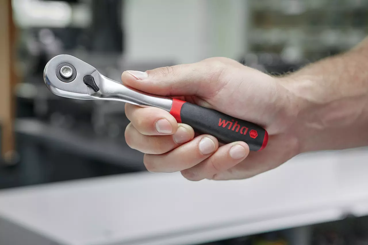 Hand holding a reversible ratchet with a black and red handle