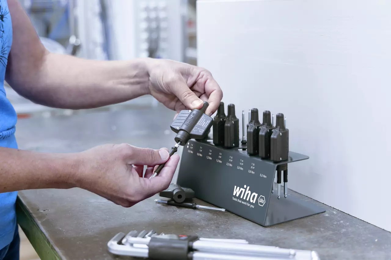 Person using a torque tool set with multiple attachments on a workbench.