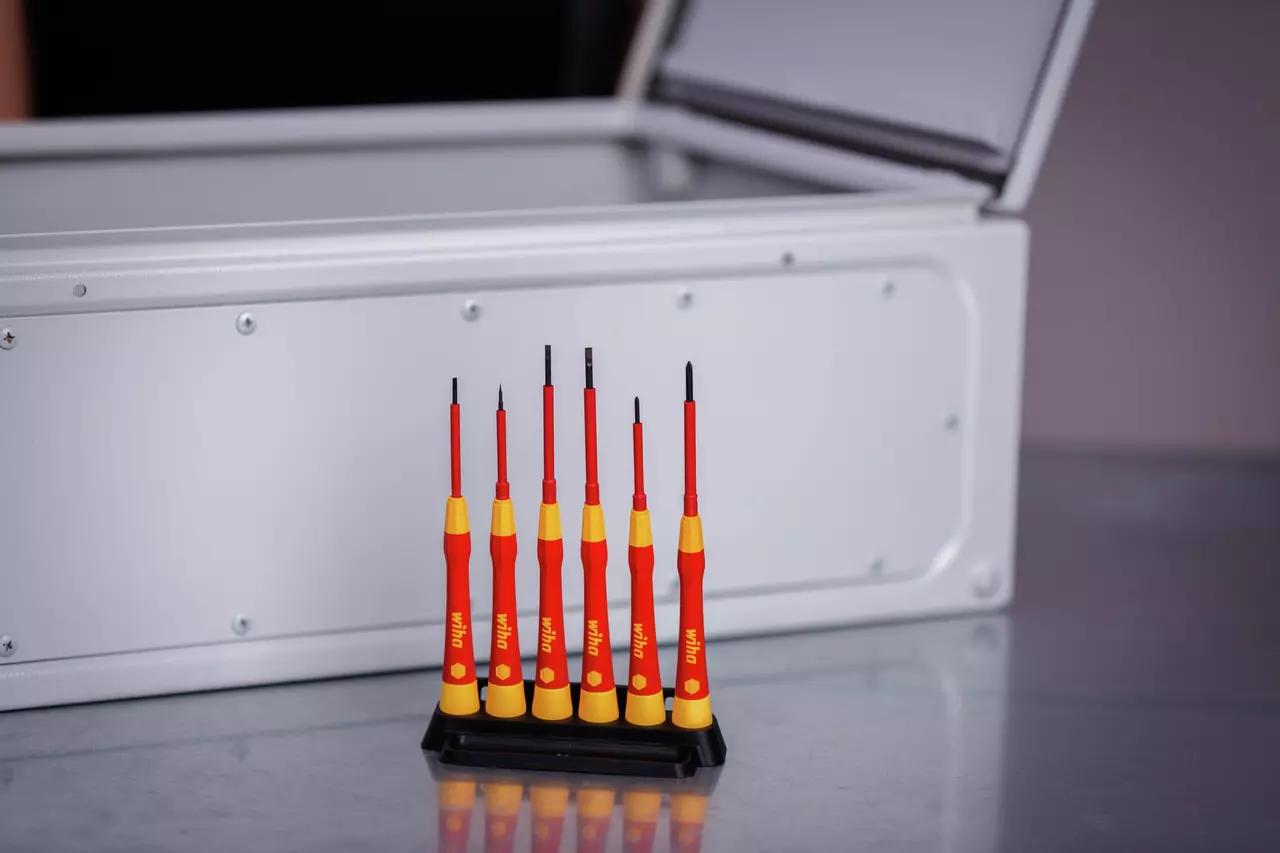 Set of six red and yellow precision screwdrivers in a black stand