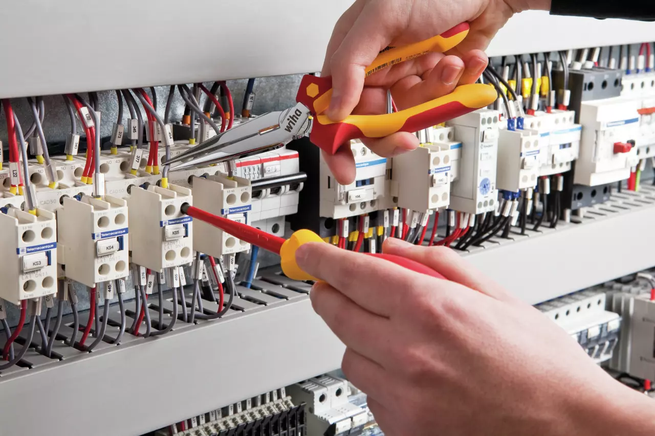 Person using pliers and screwdriver on electrical panel