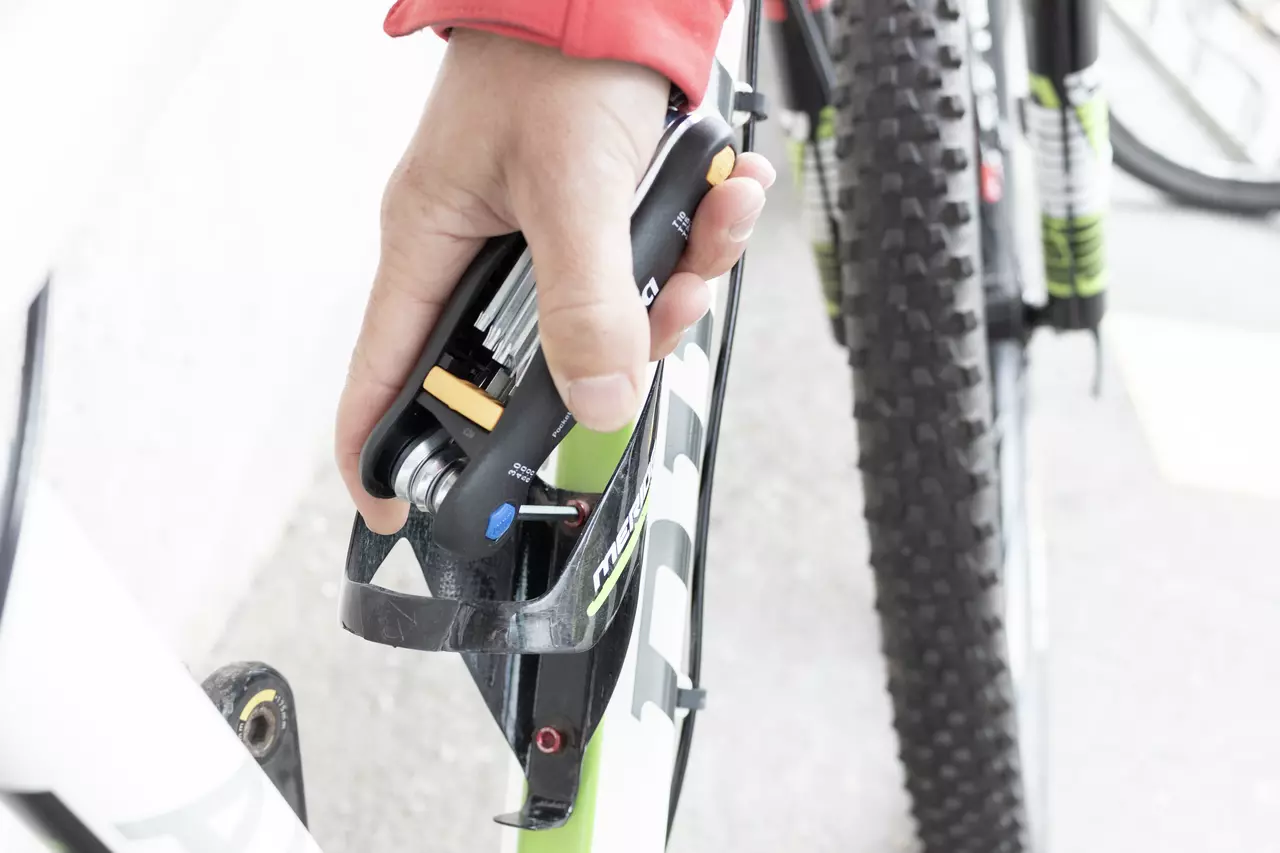 Hand using multitool to adjust bicycle part