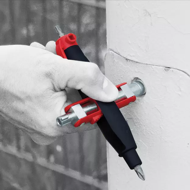 Hand using a red and black multitool to adjust a bolt in a metal surface.