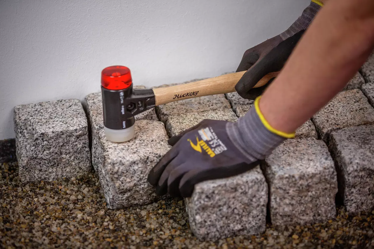 Person using a mallet to adjust paving stones