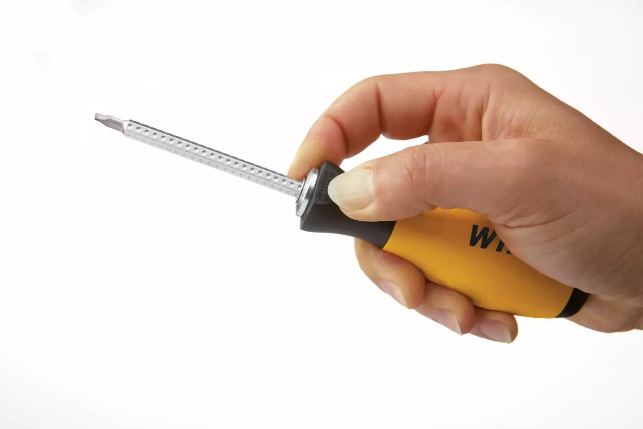 Hand holding a yellow and black screwdriver with a metal shaft