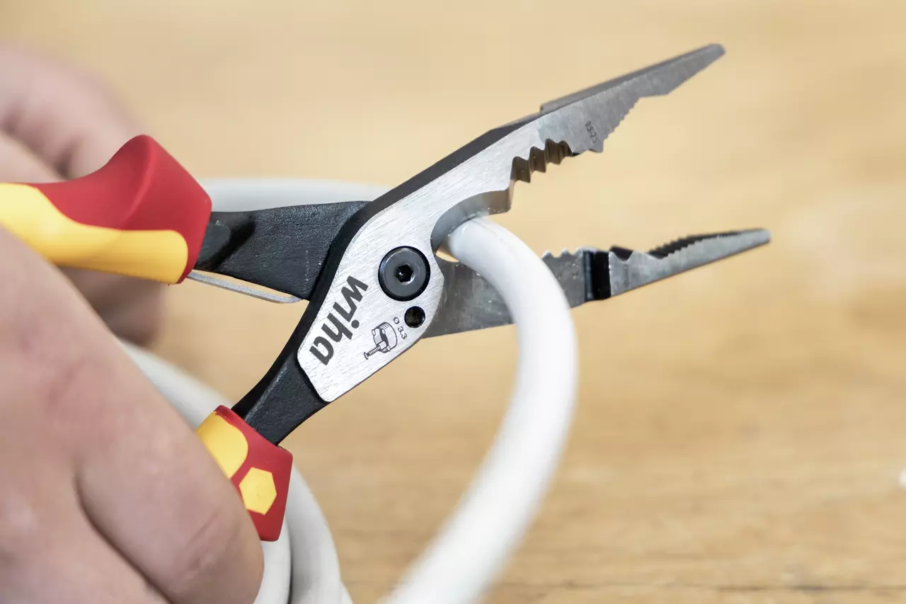 Tang met rode en gele handvatten die een witte kabel vasthoudt.