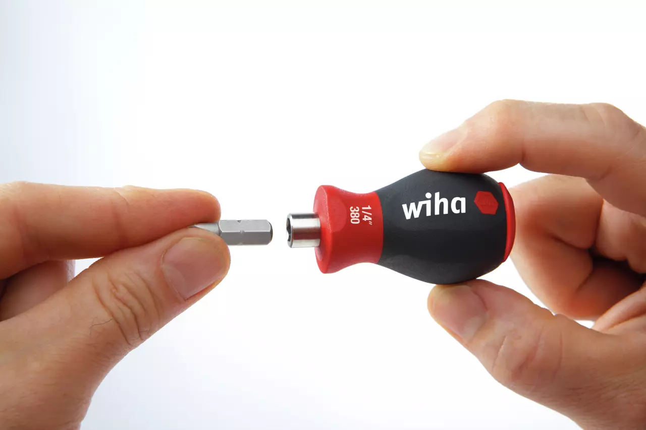 A hand holding a stubby screwdriver with a bit being inserted