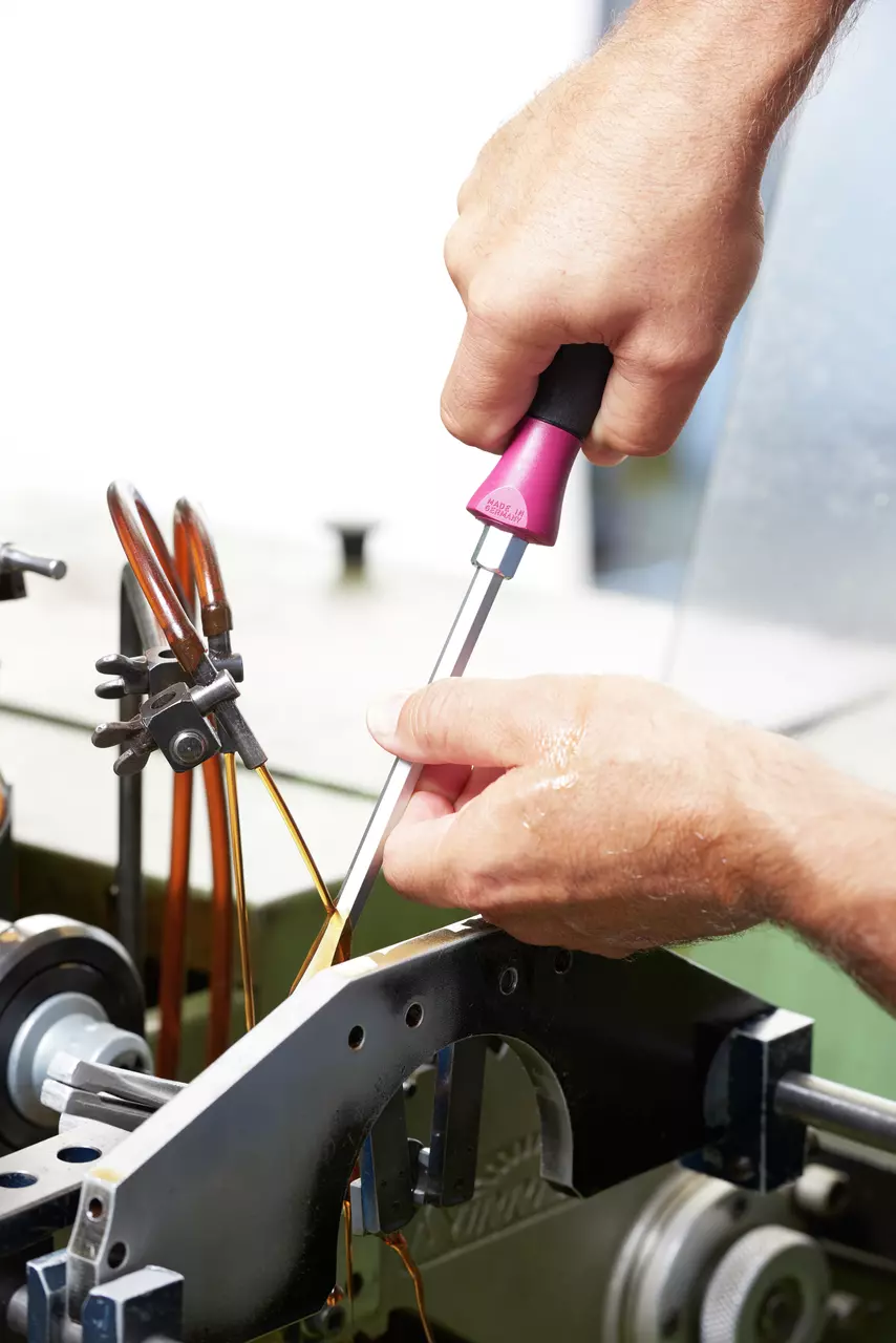 Person using a screwdriver on a machine part