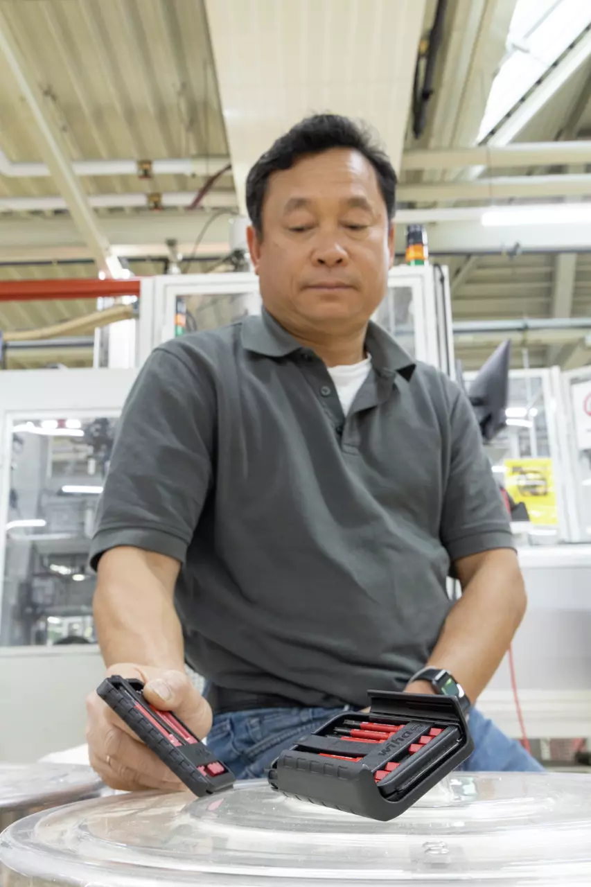 A person holding an open tool box with red screwdriver bits.