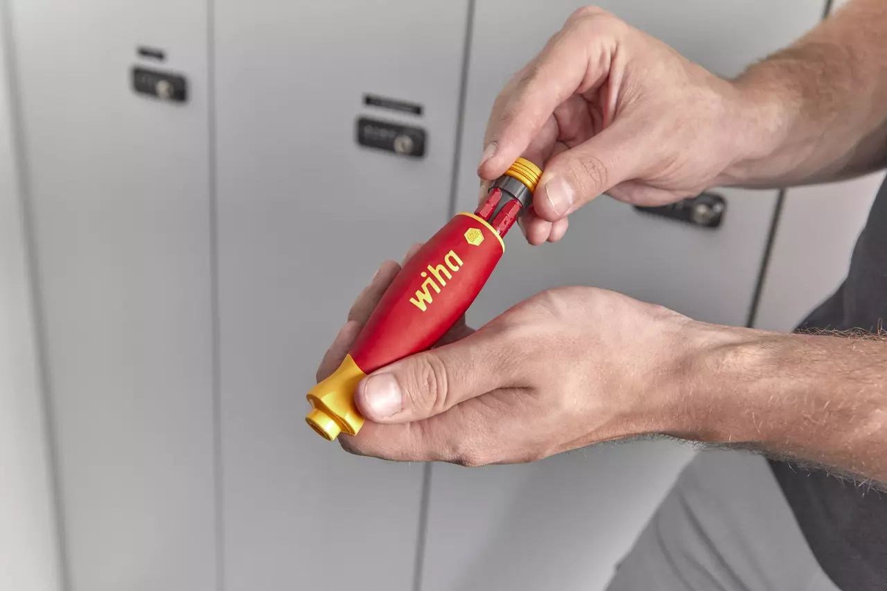 Person holding a red and yellow electric screwdriver with a bit magazine