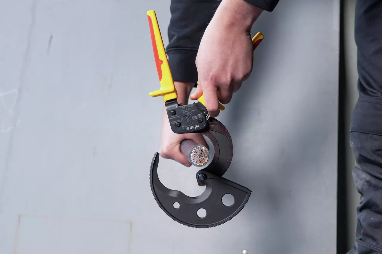 Person using a ratchet cable cutter on a thick cable