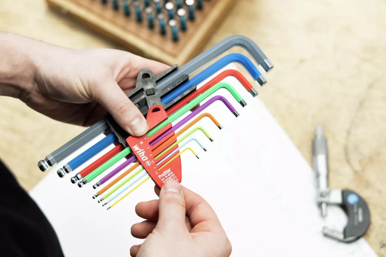 Person holding a set of colorful L-keys in a red holder