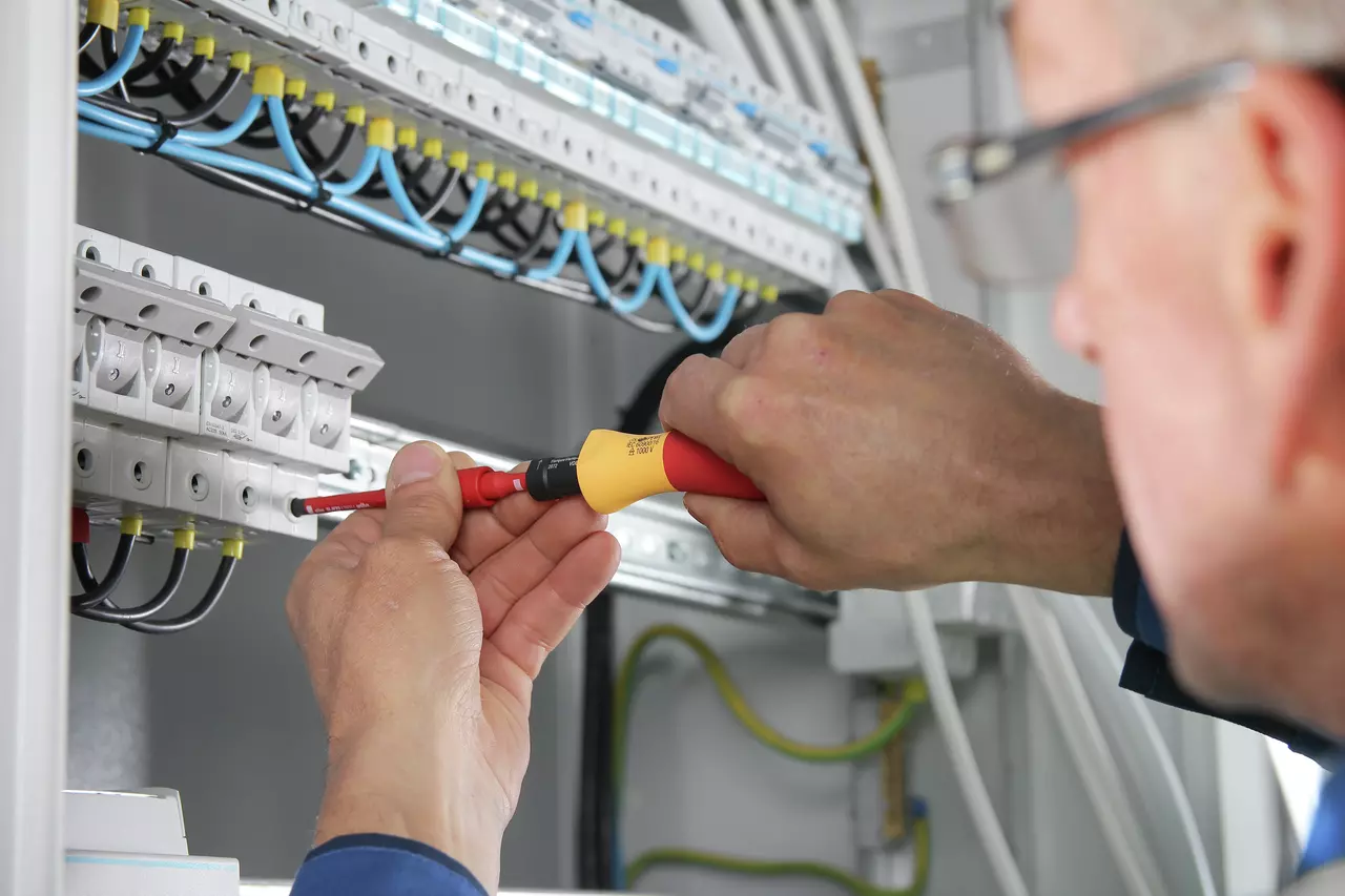 Person using an electric screwdriver on electrical panel