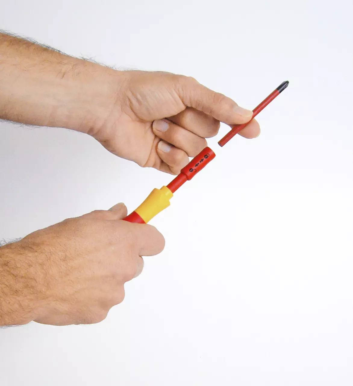 Hands holding and assembling a red and yellow screwdriver with a removable bit.