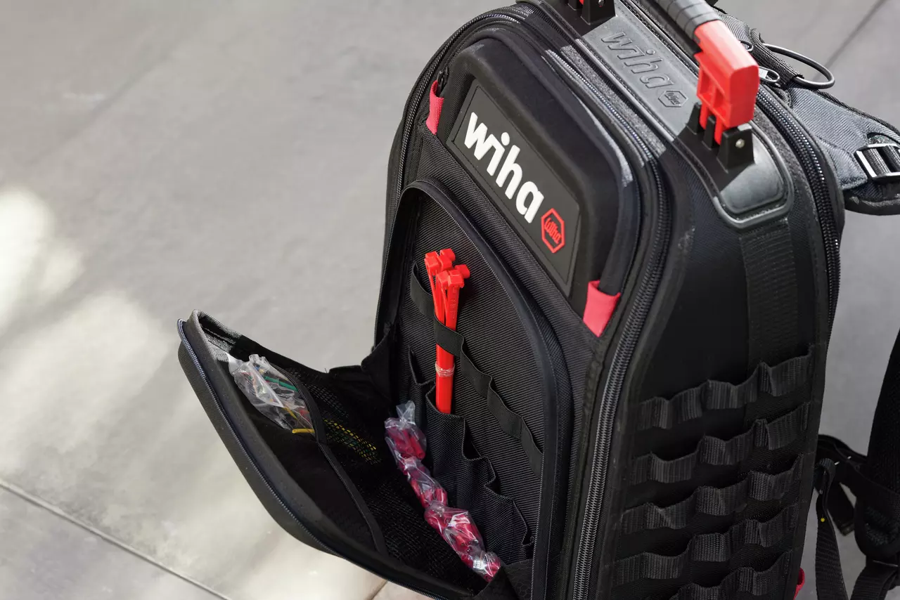 Black tool backpack with red accents, open to show tool compartments and storage pockets.