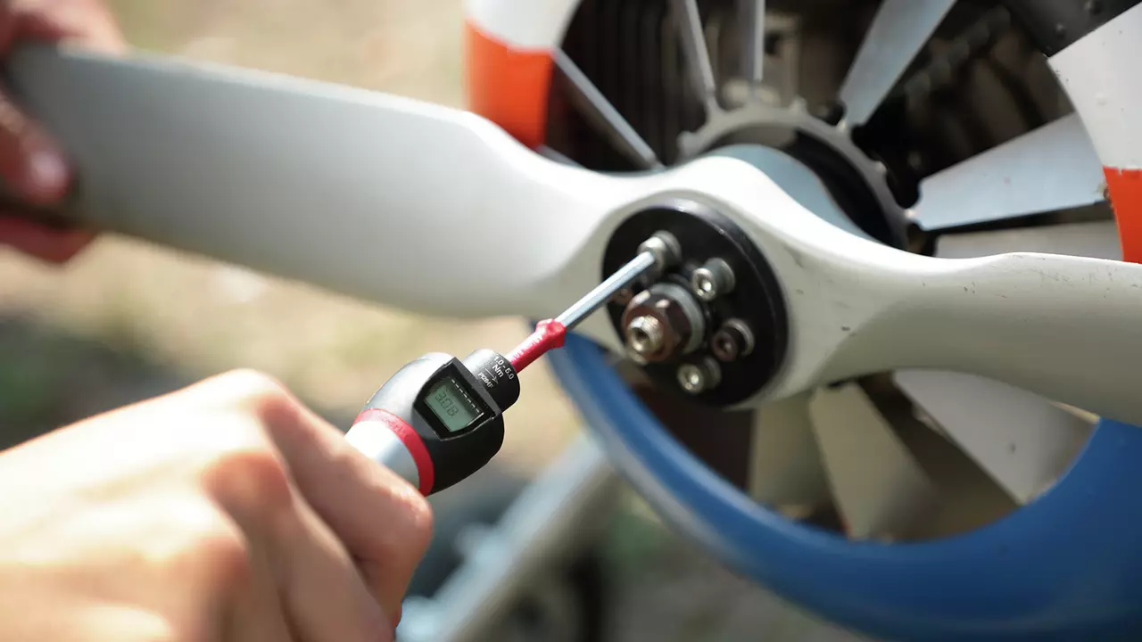 Person using a torque screwdriver to adjust a bolt on an airplane propeller.