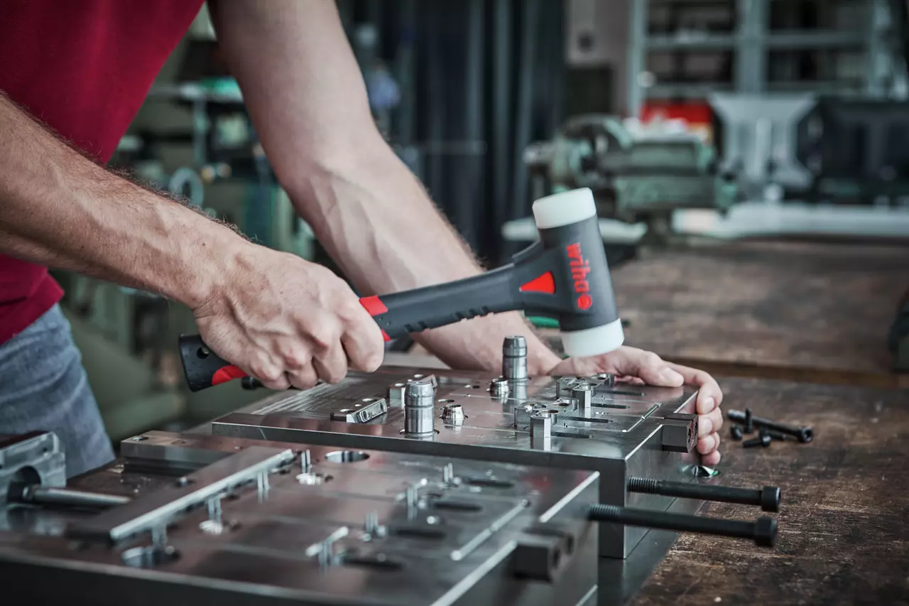 Person verwendet einen Schonhammer an einer Metallkonstruktion