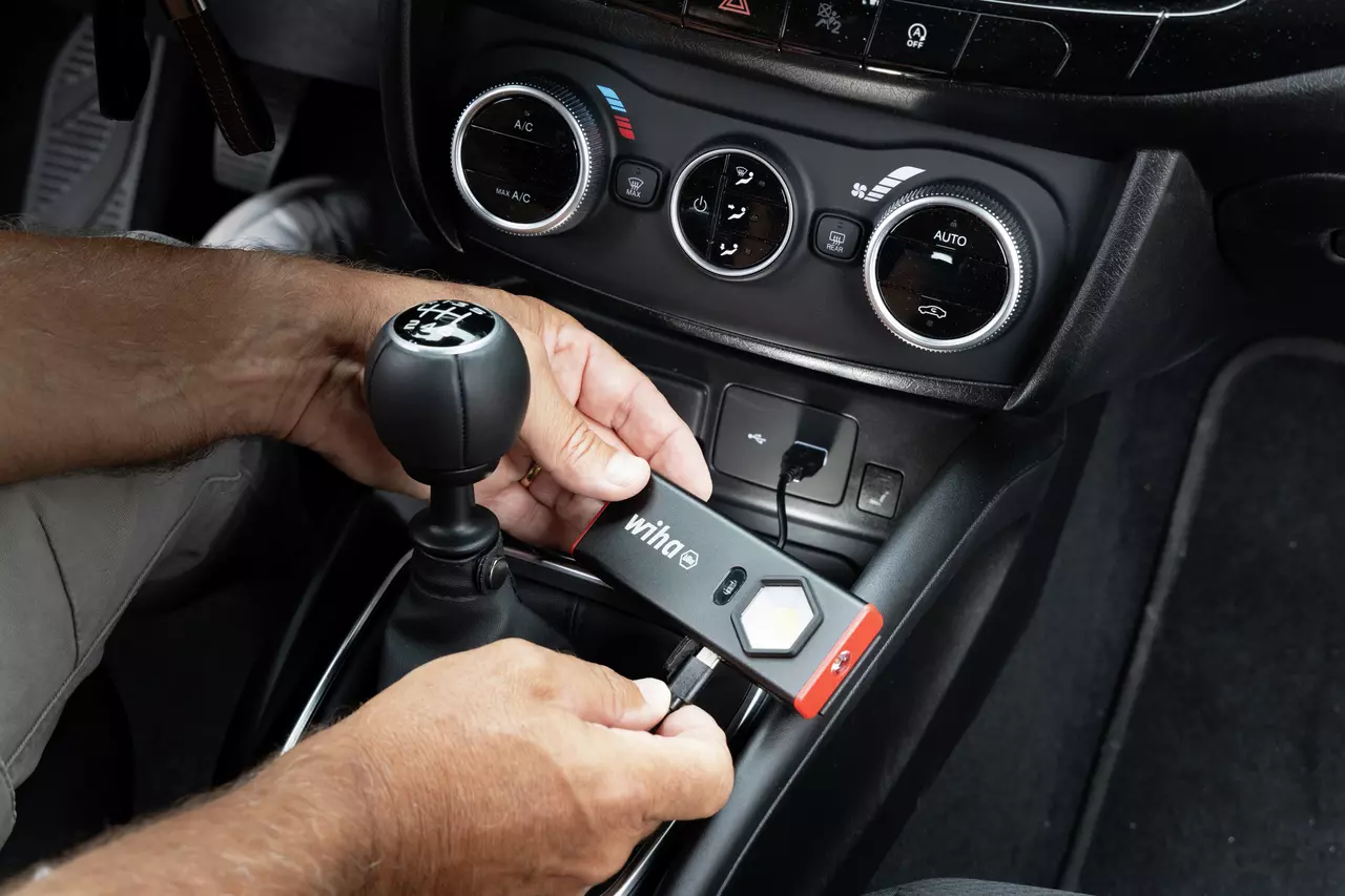 Person lädt eine Taschenlampe im Auto über USB auf