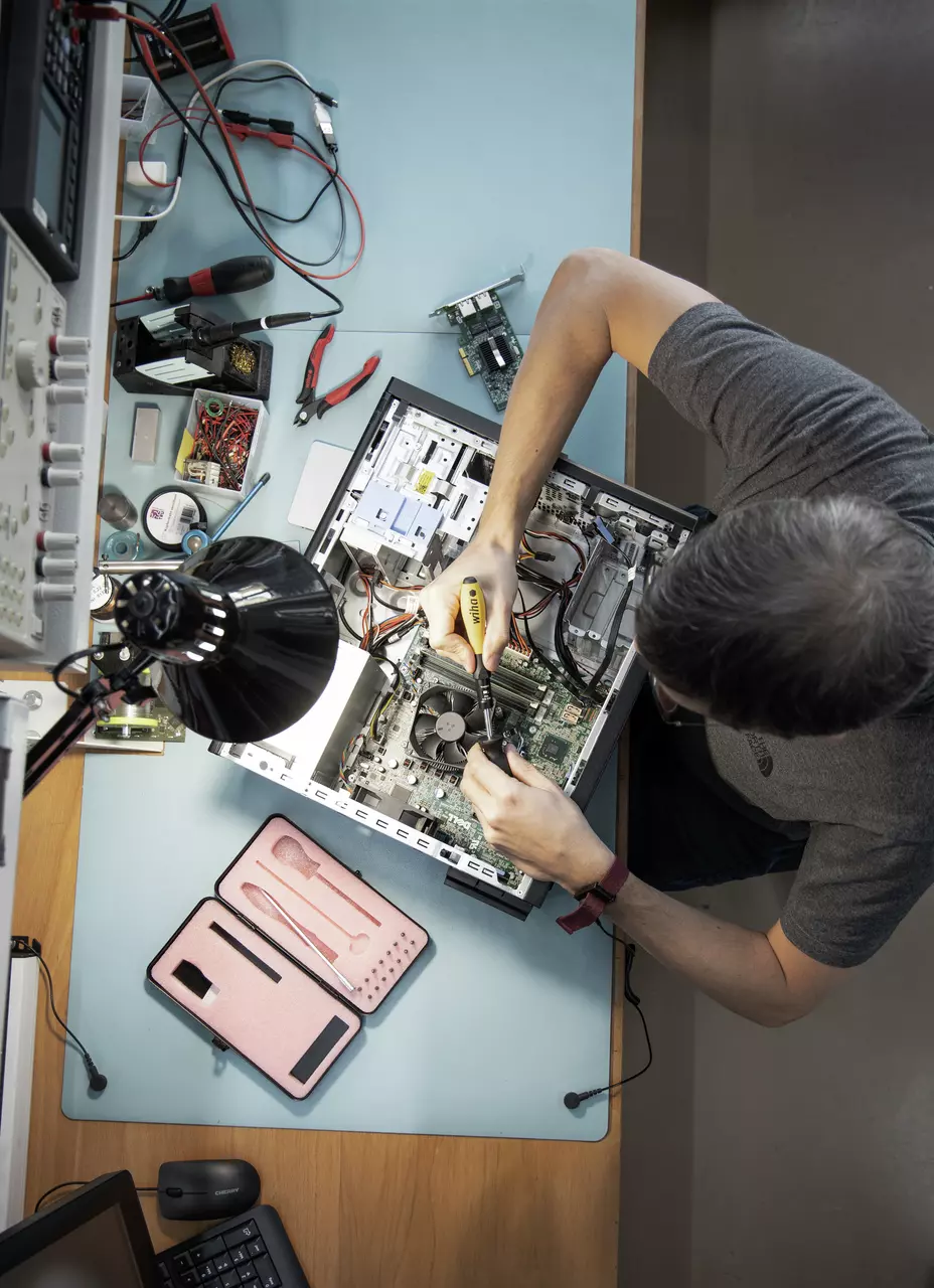 Personne travaillant sur un boîtier d'ordinateur ouvert avec des outils sur une table