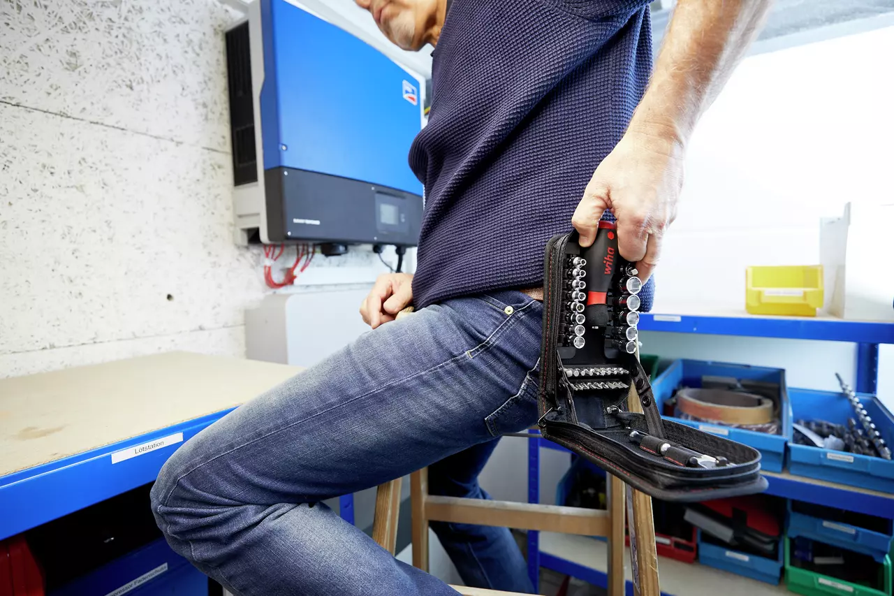 Person holding a socket set case in a workshop environment.