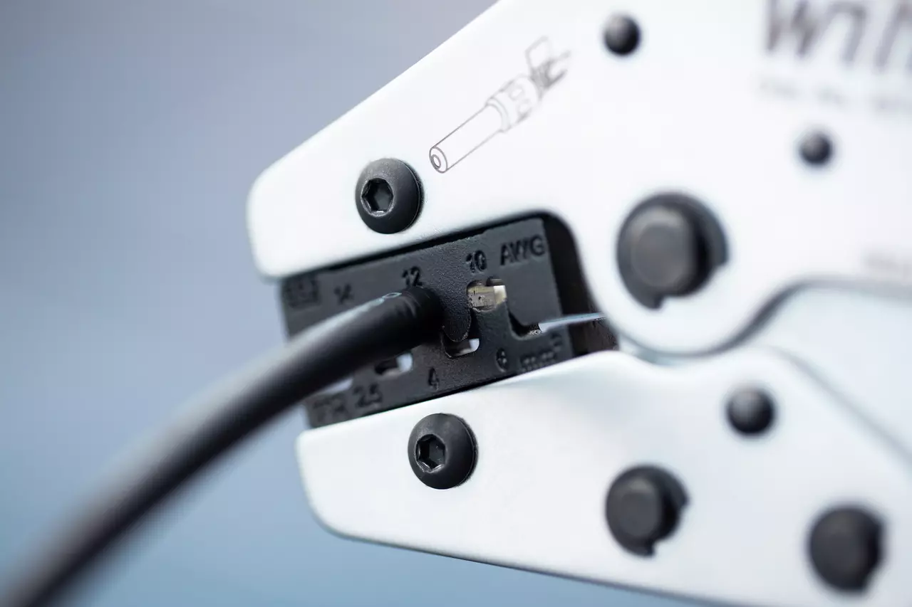 Nærbillede af et krympeværktøj med indsat kabel, fokus på kæben og målemarkeringerne.