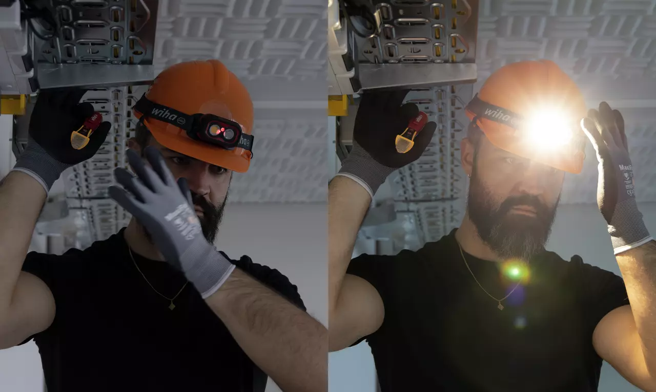 A person wearing an orange helmet with a headlamp, holding a tool, working on a ceiling structure.