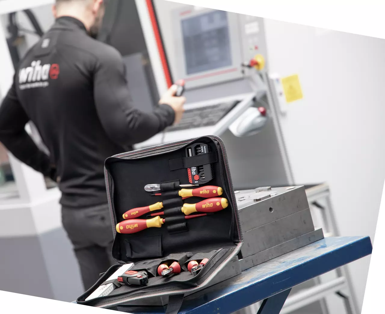 Tool set in open case on table, person working on machine in background.