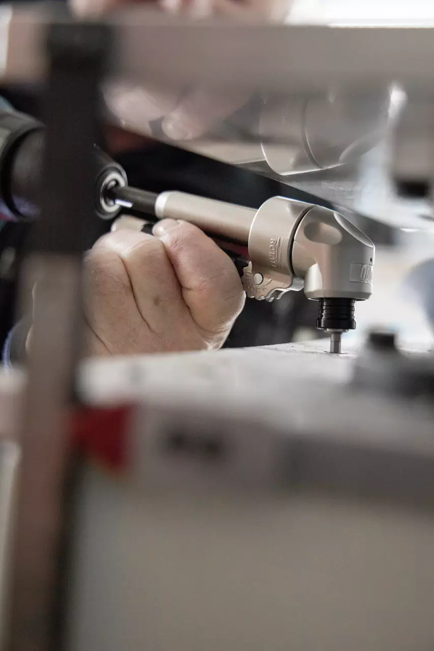A person uses a handheld tool on a surface, focusing on precision work.