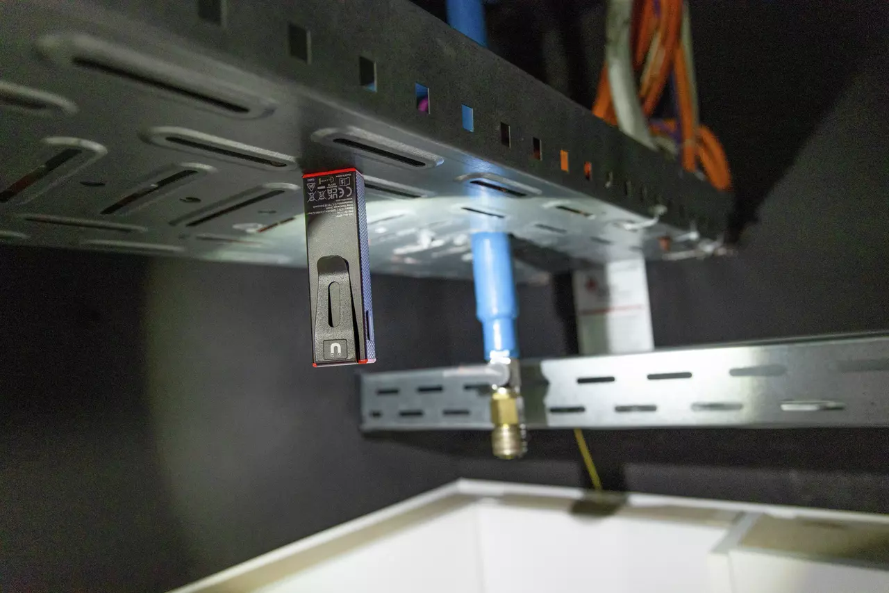 Black and red magnetic tool attached to a metal shelf underside.